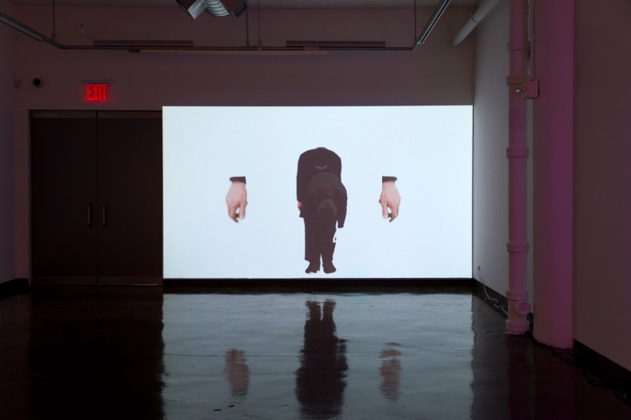 Image projection in a dark room of two men bowing and an image of a hand on the left and right side of men
