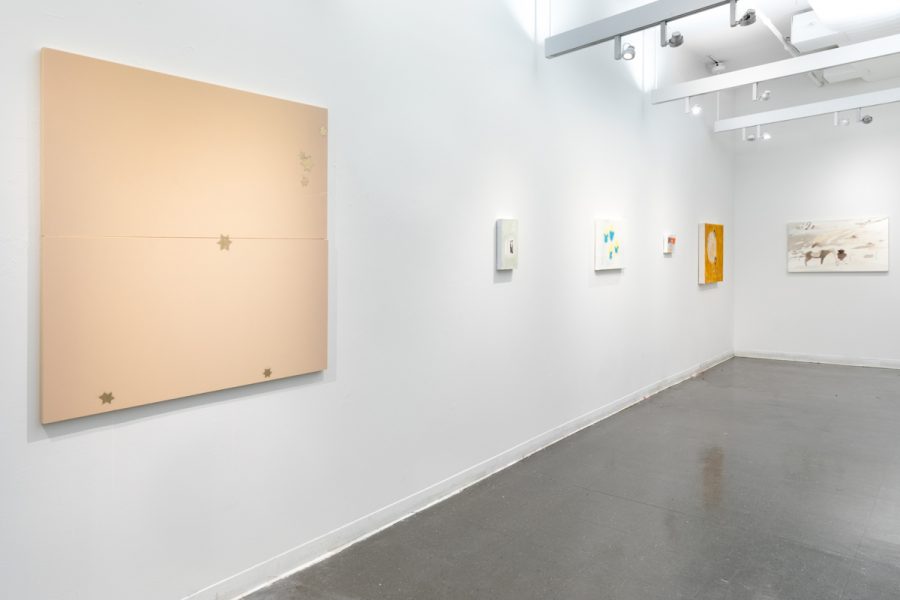 Installation view of multiple paintings by Dana Avendano. Abstract images with different hues of color and geometric shapes.