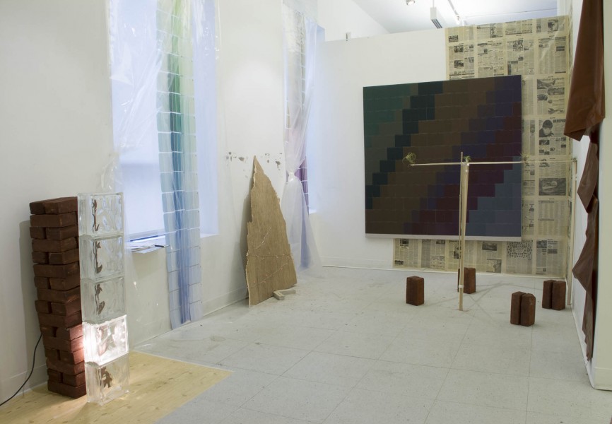 Installation view of bubble wrap, a large-scale canvas, and bricks with a light shining through a transparent material at the base of the brick structure.