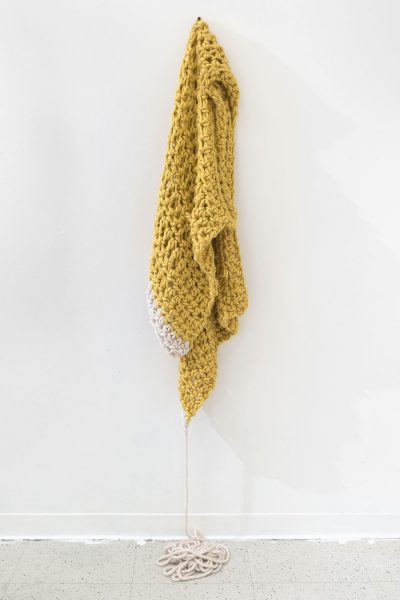 Wall mounted weaving made of yellow and white wool and fabric.