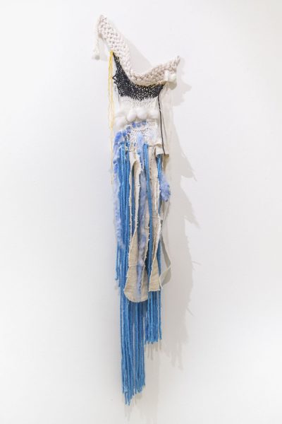 Wall mounted weaving made of white blue and black wool and fabric.