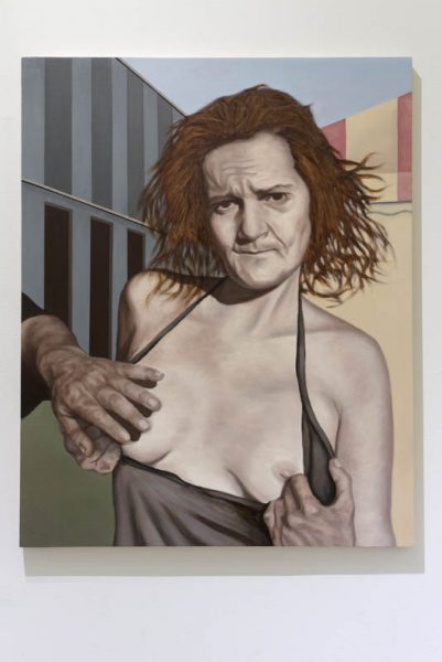 A painting that represents a woman who uncovers her breasts, and a man touches one of them. She has short hair till the shoulders, a grey shirt, and in the back are buildings painted in grey with  vertical stripes and orange with red vertical stripes