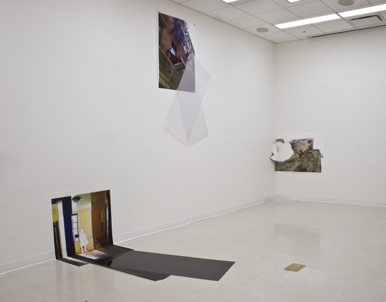 Installation view of prints punted on the wall and on the floor with person shape cut-outs.