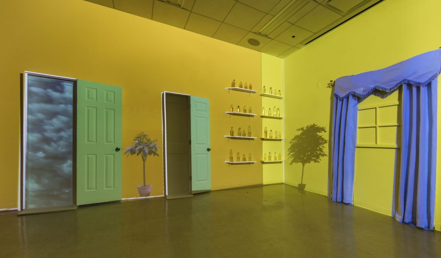 Video still of 3D modeled space, with two green doors and eight shelves with plastic water bottles on them, against a yellow wall, with purple curtains on the right hand side.