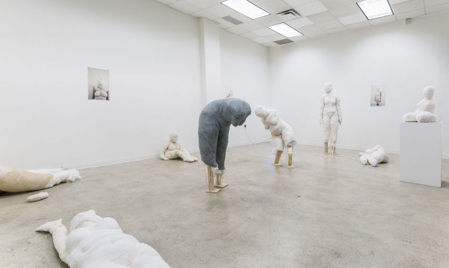 Installation shot of multiple sculptures of the female form made from stitched off-white soft fabric. Three sculptures on the floor and one on a pedestal.