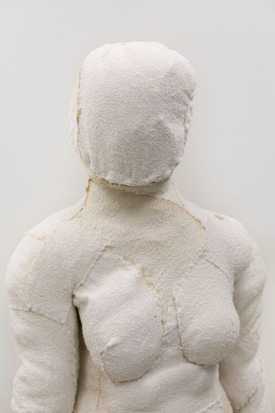 Sculpture of a woman's torso and head made of stitched off-white soft fabric.