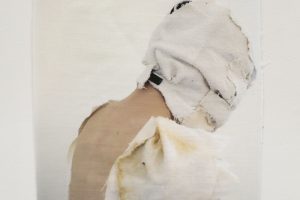 Image of a woman whose face is wrapped in cloth printed on a piece of fabric and hung on the wall.