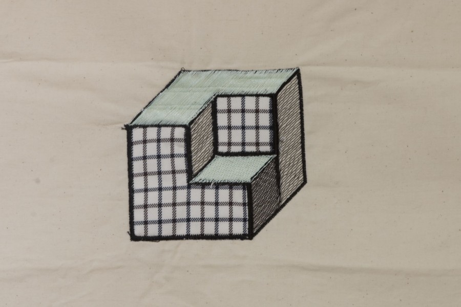 Embroidered cube shape with black lines and green tops, with a missing cube on the top right corner from a formation of four cubes