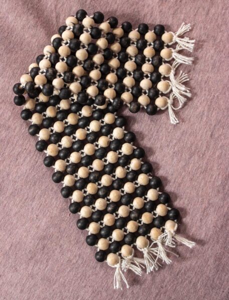 A beaded blanket made out of black and beige spheres.