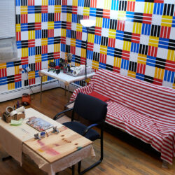 Red, blue, yellow, black and white duct tape which striped on the wall.