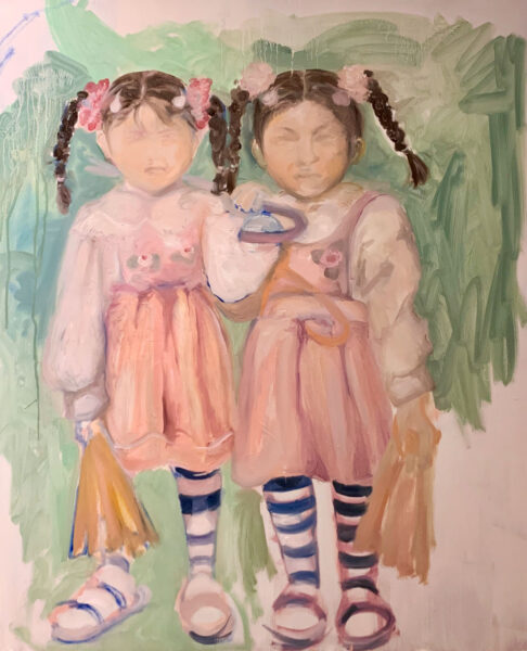 Portrait of two Asian girls with braids and striped socks on green background.