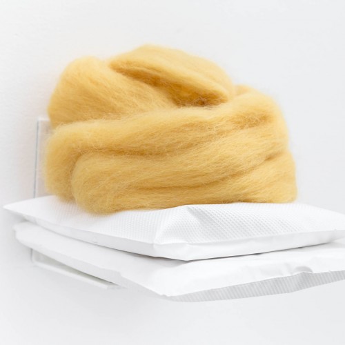 A yellow wool pile is placed on two white rectangular-shaped white plastic bags.