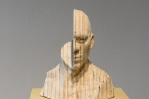 Head sculpture made of layered wood of a person with one half of the head.