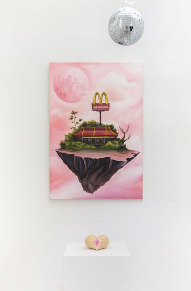 Installation shot of a painting of a piece of a world floating in pink space with a hanging disco ball and a pedestal with a vaginal shape resting on it.