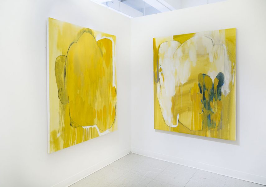 Two paintings installed in a corner of yellow with a blue shape in the foreground and a medium yellow background, very drippy.