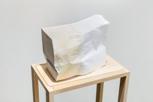 A sculpture by Hanjun Zhang. A rectangular object with muted hues placed on a wooden table..