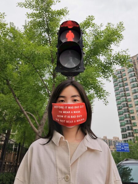 Hanni Huang, Quarantine Diary Video still of woman wearing a slogan mask.