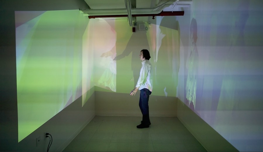 A person sitting in the middle of a room with images projected on the walls around them