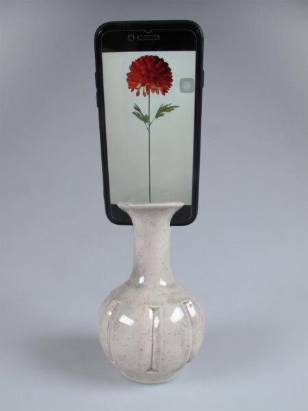 Ceramic vase with Iphone inserted into it showing a virtual flower growing on screen. 