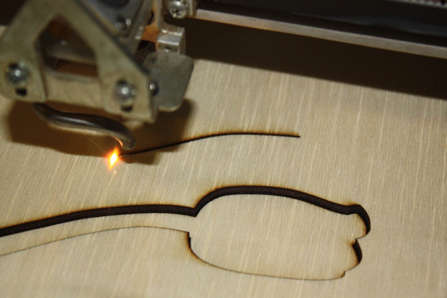Close-up of a CNC machine cutting an organic shape in a wooden board.