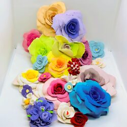 A coloful pile of ceramic flowers with bright blue, yellow, red, green and pink colors.