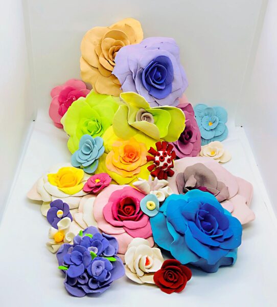 A coloful pile of ceramic flowers with bright blue, yellow, red, green and pink colors.
