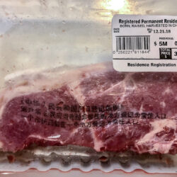 A packed piece of steak with  a barcode label reading "Registered Permanent Resident, Born, Raised, Harvested in China", and priced at $3.5M