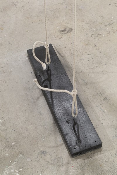 A black swing with white rope viewed from e higher angle.