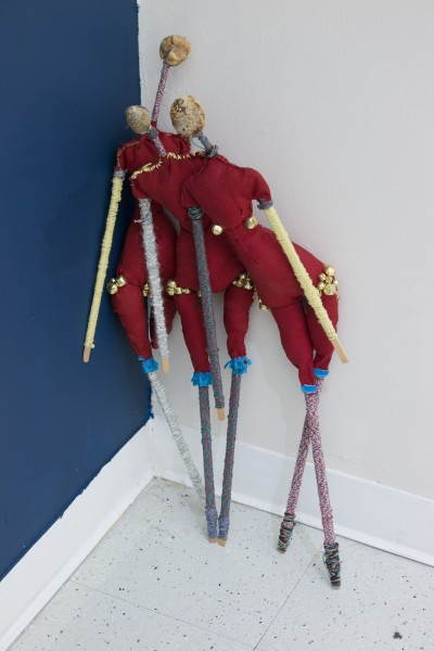 Dolls made of red fabric and long wood sticks covered with cloth for hands and legs.