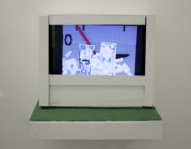 Small screen with an image of two caricatures on a blue vertical stripes background, with a white wood frame placed on a shelf with a small green fabric on the shelf