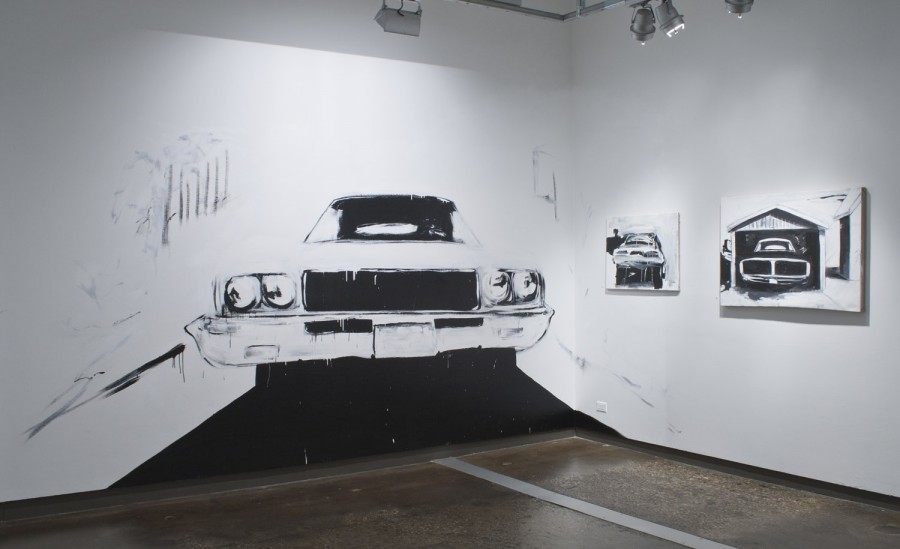 A large-scale car painting on the wall illuminated from the ceiling, and two other car paintings hung on the right wall, all painted in black and white.