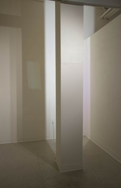 A view of a white column with its top side illuminated by a white light.