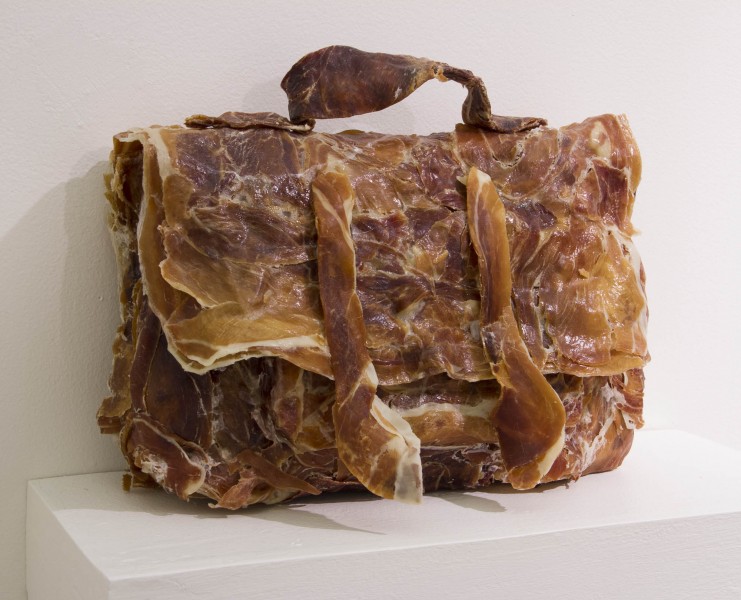 A close view of a handbag made out of bacon sitting on a shelf.