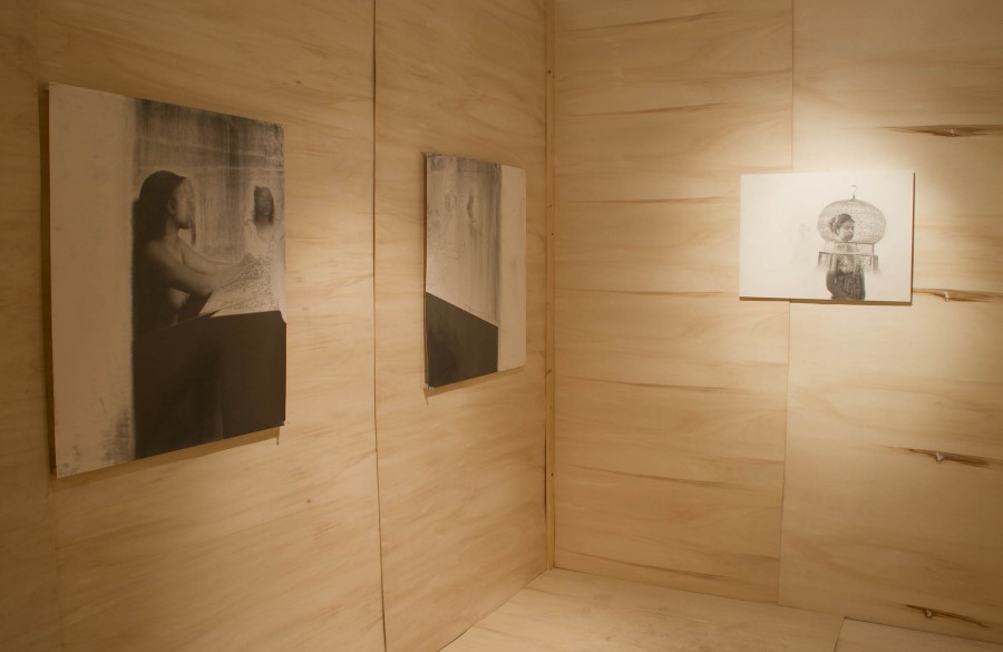A view of three graphite drawings installed on wooden panels.