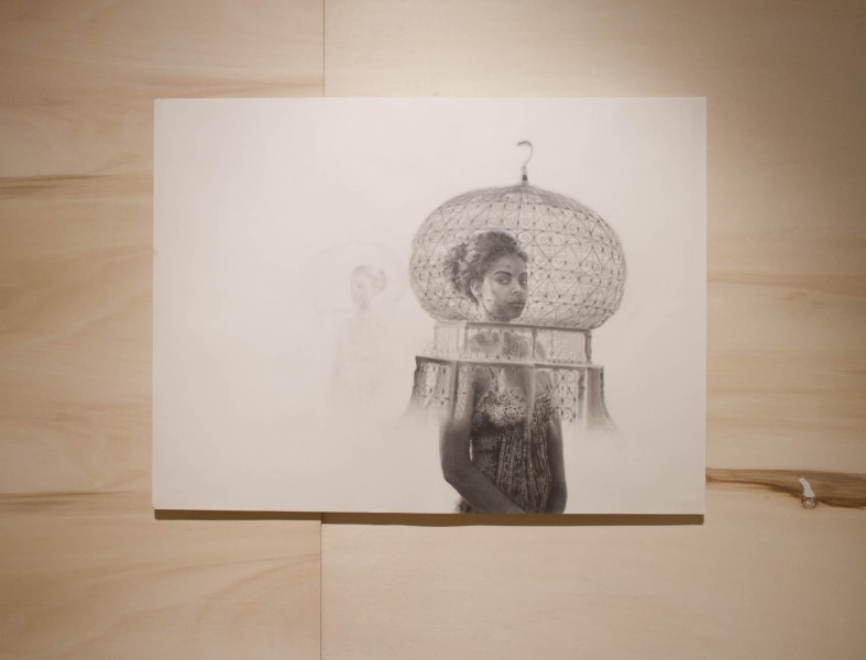 Graphite drawing of a person with their head in an oversized transparent globe. The drawing is placed on a wood panel.