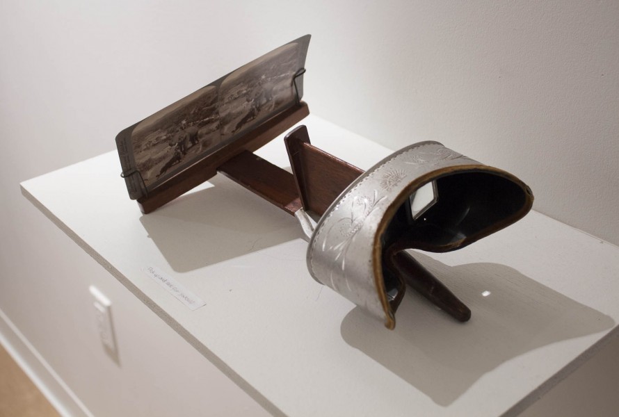 Stereoscopic device with an image in front of it, sitting on a white shelf.