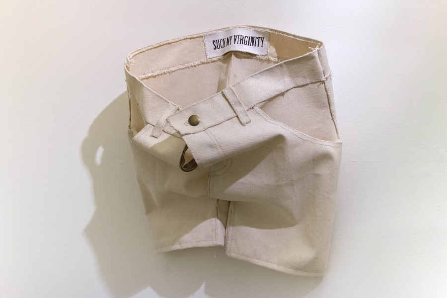 A view of a pair of short pants made of beiger fabric with the zipper open and the button closed.