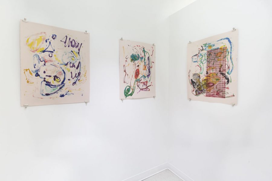 Three paintings installed in a corner of abstract purple, yellow, and green lines, held on the wall with alligator clips.