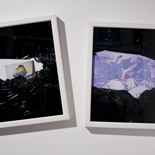 Two white wooden frames are installed on a wall, with one frame at an angle. One has a photograph with a black organic material covering the top and the bottom of the frame, and the other has an illustration with blue and white shapes covered at the top and the bottom with a black organic shape.
