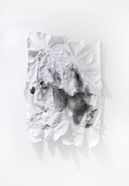 Crumpled white napkin stained with black ink crumpled on the wall.