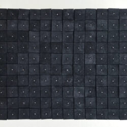 A large black sculpture in the form of a square. The shape is made up of smaller black charcoal squares next to each other, with each having a small dot in the center.