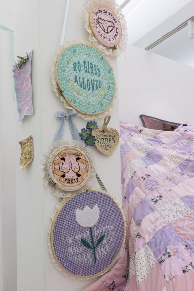 Flower, text, and pants surrounded by circular text embroidered on various circle shapes in different sizes, on violet, green, pink backgrounds.