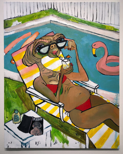 ET, the character from the 1982 film, is crudely painted in a red bikini on a yellow and white striped lawn chair. They are looking over a pair of sunglasses and drinking out of a glass with an umbrella. Next to them is a small table, on it, a copy of Playboy magazine and sunblock labelled “SPF whatever”. There is a fence and a pool with pool noodles and a flamingo floatie in the background.