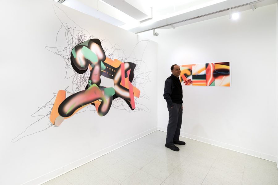 Installation view of artwork by Li Zeng. Colorful paintings or irregular shape, with geometric forms and digital textures. A person is standing in the space that helps to indicate the scale and size of the artwork.
