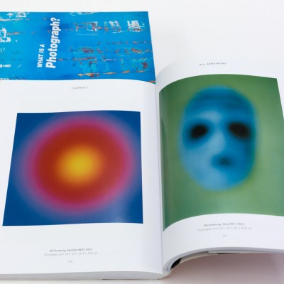 Two closed book and one open spread showing colorful digital prints.