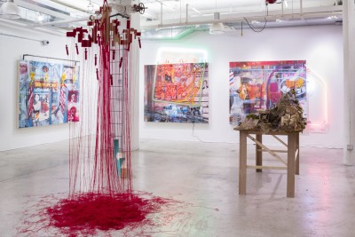 Installation view of wooden sculpture, wooden structure hanging on the ceiling with red thread going on to the floor, and other abstract paintings.