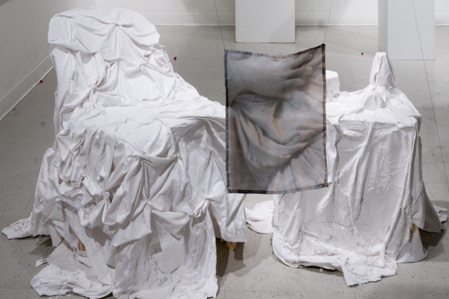 Install shot of sculpture, a chair covered in white fabric.