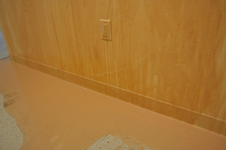 Wall painted in orange, and the paint is dripping from the wall to the floor.