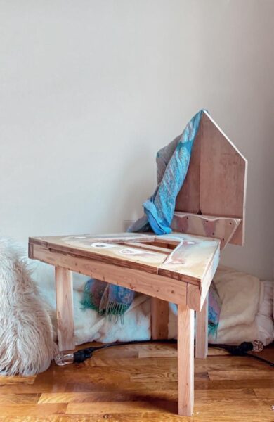 Triangular chair made of wooden draped with a blue fabric.