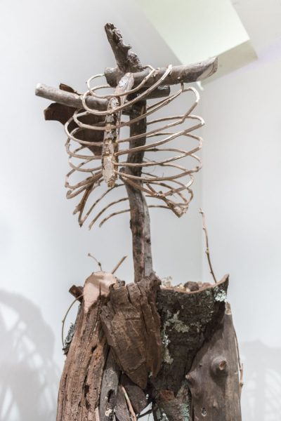 Detail shot of a sculpture of human ribs, shoulders, and hips made of twigs and sticks.